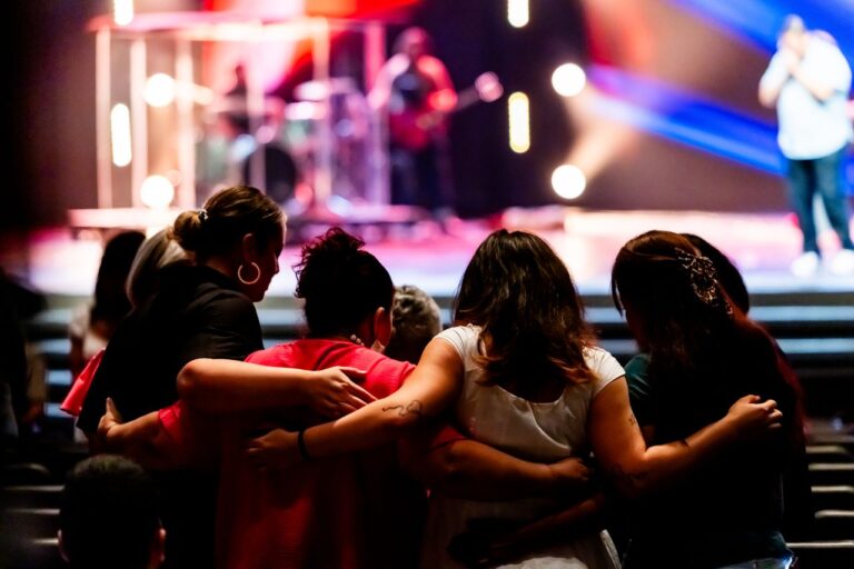 A diverse group embracing at a live music event, creating a sense of unity and togetherness.
